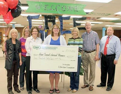 staff and students taking picture with big check