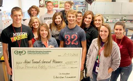 staff and students taking picture with big check