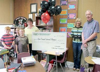 staff and students taking picture with big check