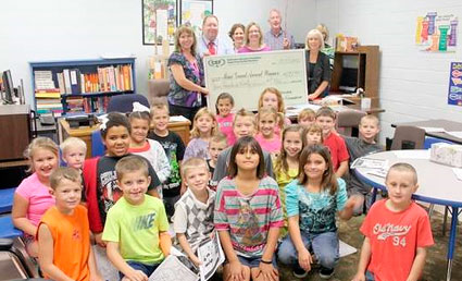 staff and students taking picture with big check