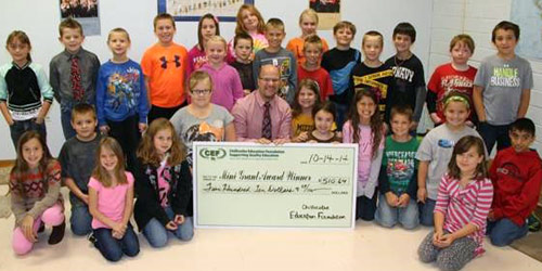 staff and students taking picture with big check