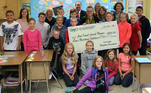 staff and students taking picture with big check