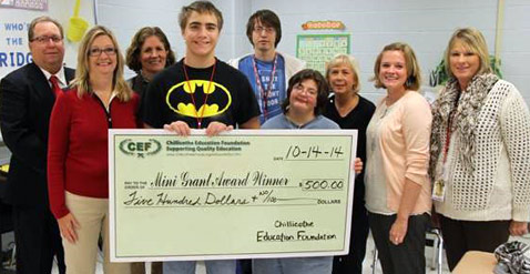 staff and students taking picture with big check