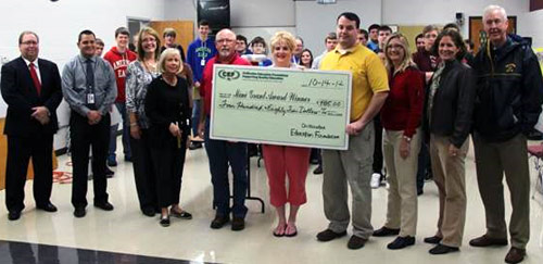 staff and students taking picture with big check