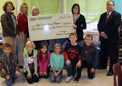 staff and students taking picture with big check