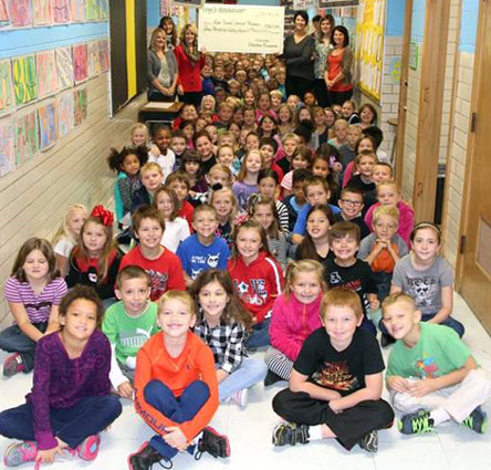 staff and students taking picture with big check