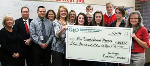 staff and students taking picture with big check