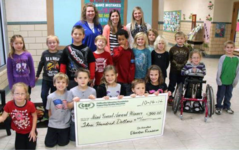 staff and students taking picture with big check