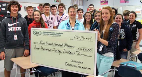 staff and students taking picture with big check