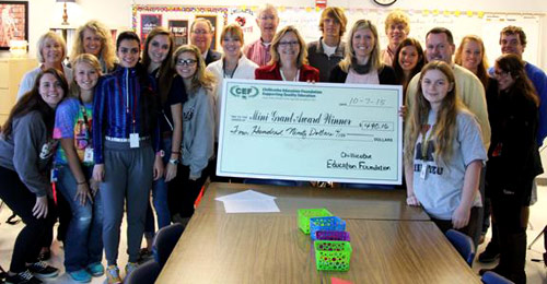 staff and students taking picture with big check