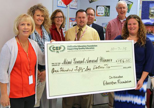 staff and students taking picture with big check