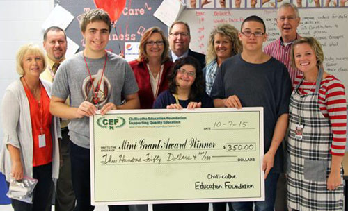 staff and students taking picture with big check