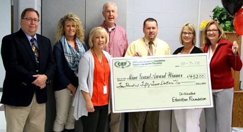 staff and students taking picture with big check