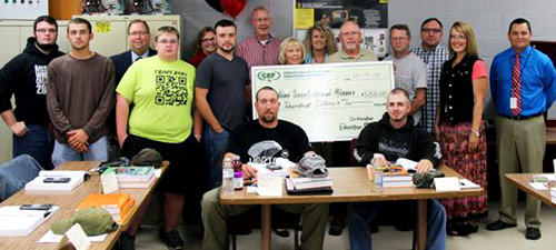 staff and students taking picture with big check