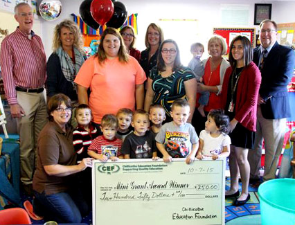 staff and students taking picture with big check