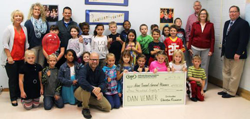 staff and students taking picture with big check