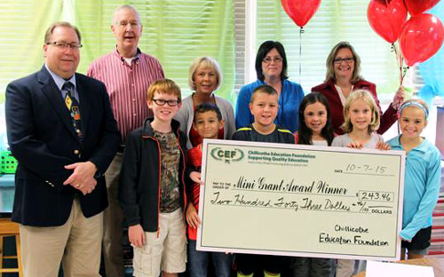 staff and students taking picture with big check