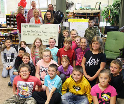 staff and students taking picture with big check