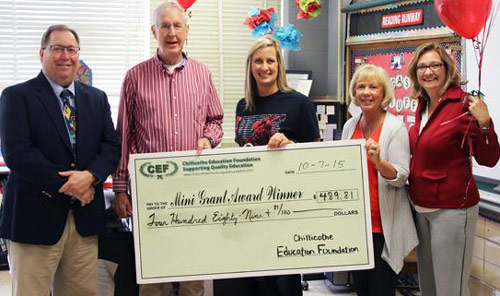 staff and students taking picture with big check