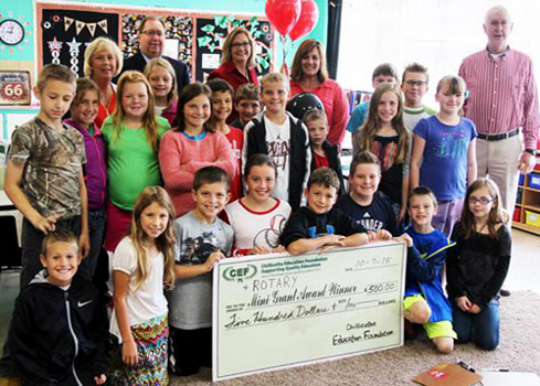 staff and students taking picture with big check