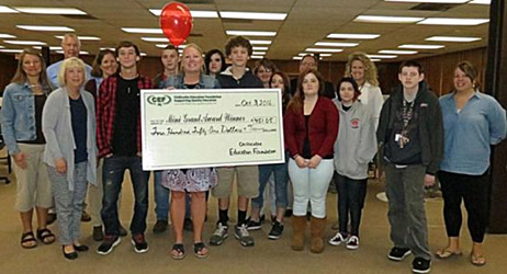 staff and students taking picture with big check