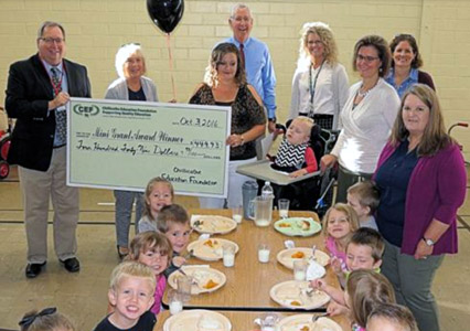 staff and students taking picture with big check