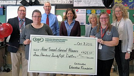 staff and students taking picture with big check