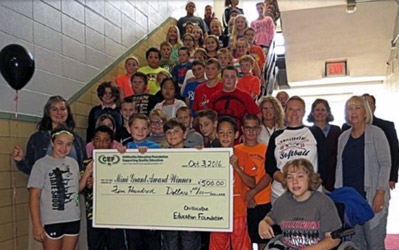 staff and students taking picture with big check