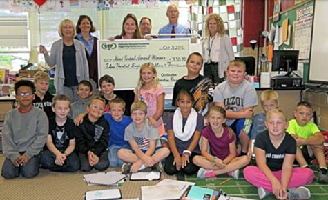 staff and students taking picture with big check