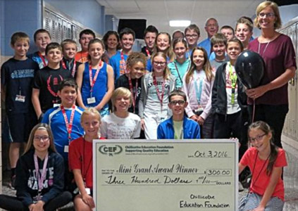 staff and students taking picture with big check