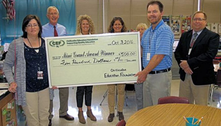 staff and students taking picture with big check