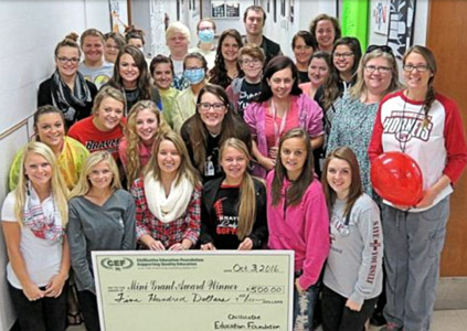 staff and students taking picture with big check