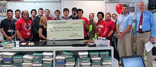 staff and students taking picture with big check