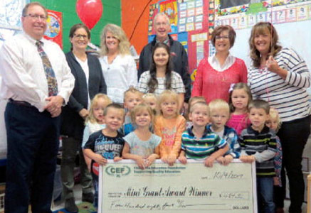 staff and students taking picture with big check