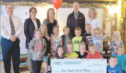 staff and students taking picture with big check