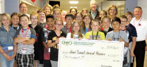 staff and students taking picture with big check