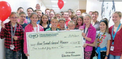 staff and students taking picture with big check