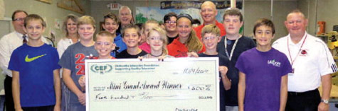 staff and students taking picture with big check