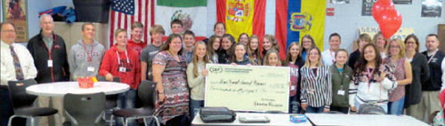 staff and students taking picture with big check