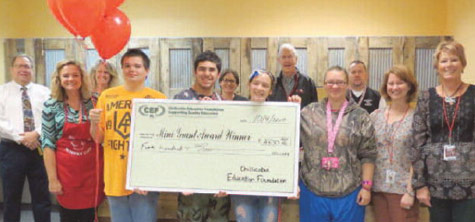 staff and students taking picture with big check