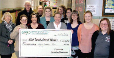 staff and students taking picture with big check