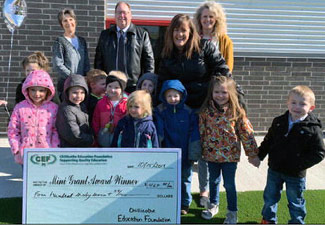 staff and students taking picture with big check