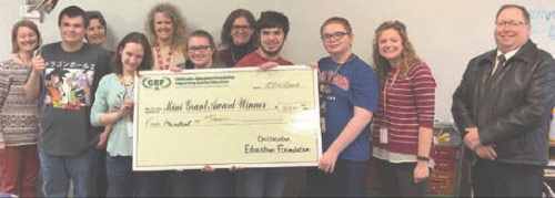 staff and students taking picture with big check