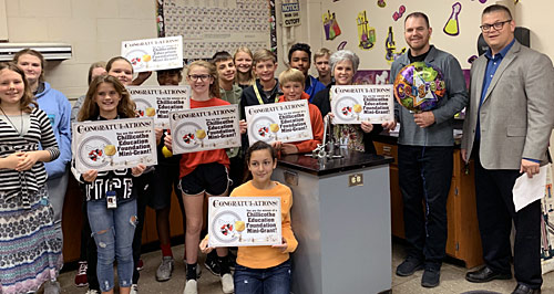 staff and students taking picture with an award