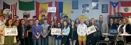 staff and students taking picture with an award