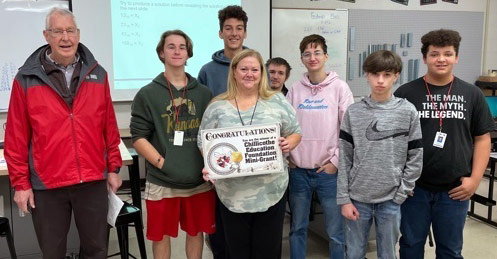 staff and students taking picture with award