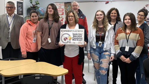 staff and students taking picture with award