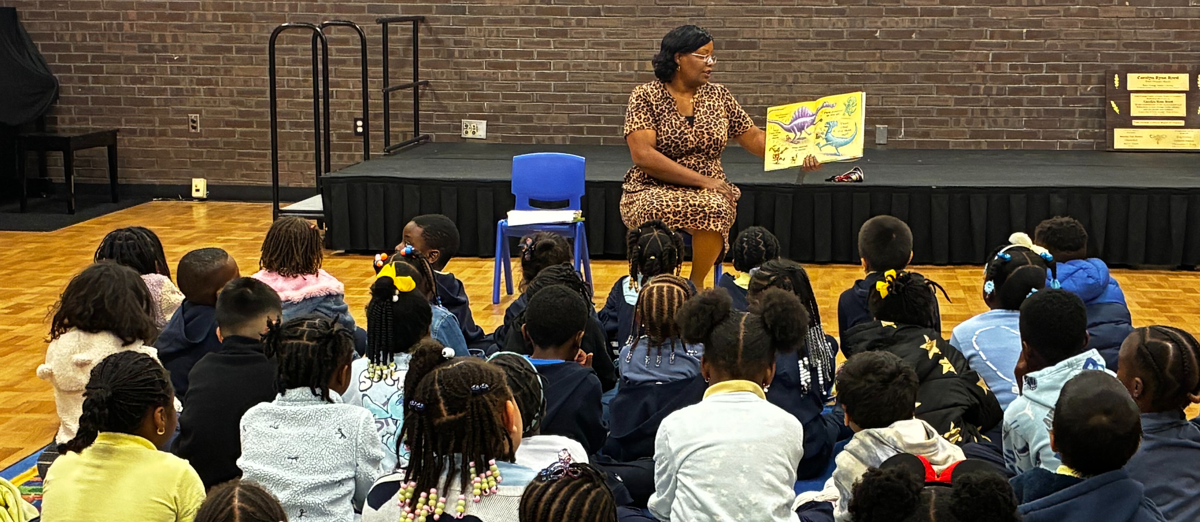 Image of person reading a book to a group of student