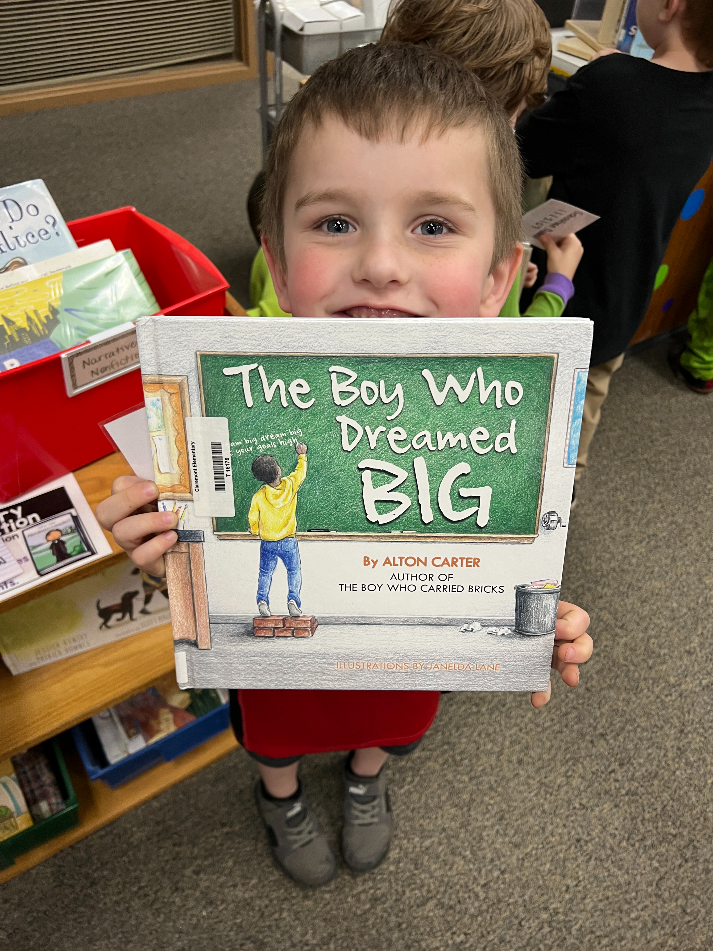 Little boy in the library in line to check out his book.