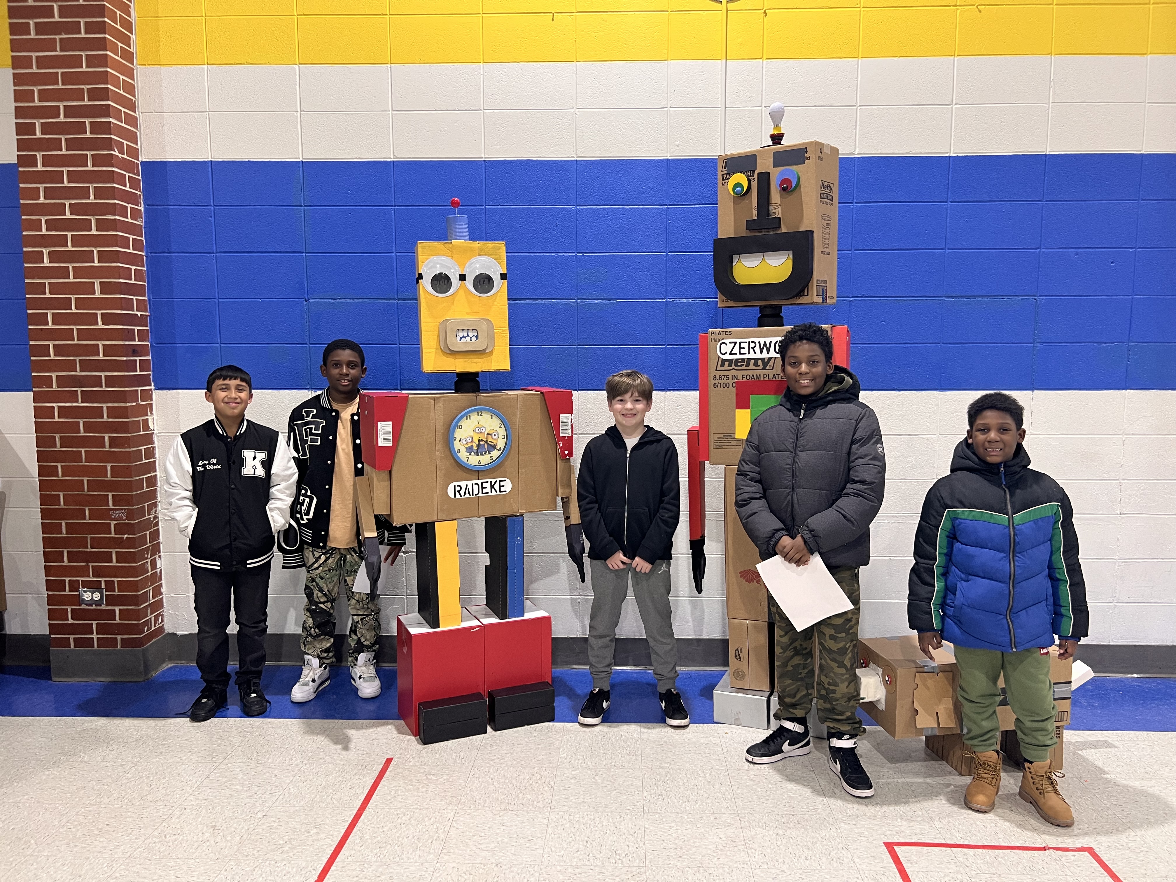 5 students standing in front of a robot they created. 